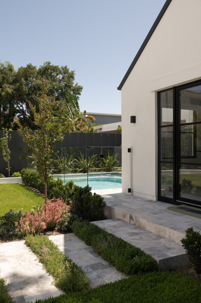 Rendered exterior with while walls, black windows, minimal landscaping and a glistening pool.