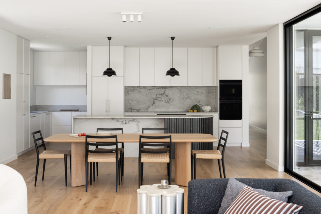 White kitchen with grey stone splash-back and oak wood floors